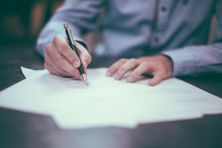 Photograph of a man filling out documents by hand.